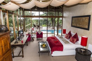 Una habitación amplia con una cama grande, un comedor y vistas a una piscina.