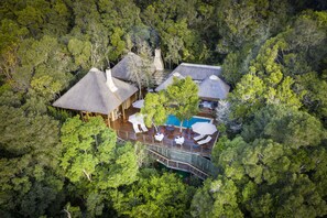 An aerial view of a resort with multiple buildings surrounded by dense forest, featuring a swimming pool and outdoor seating areas. - Trogon House and Forest spa (The Crags)