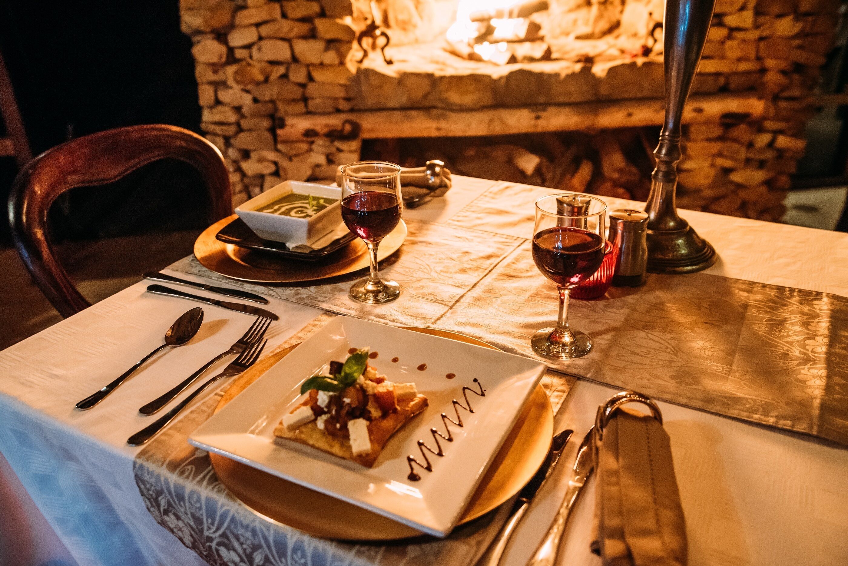 A dining table set with a plate of food, wine glasses, and cutlery.