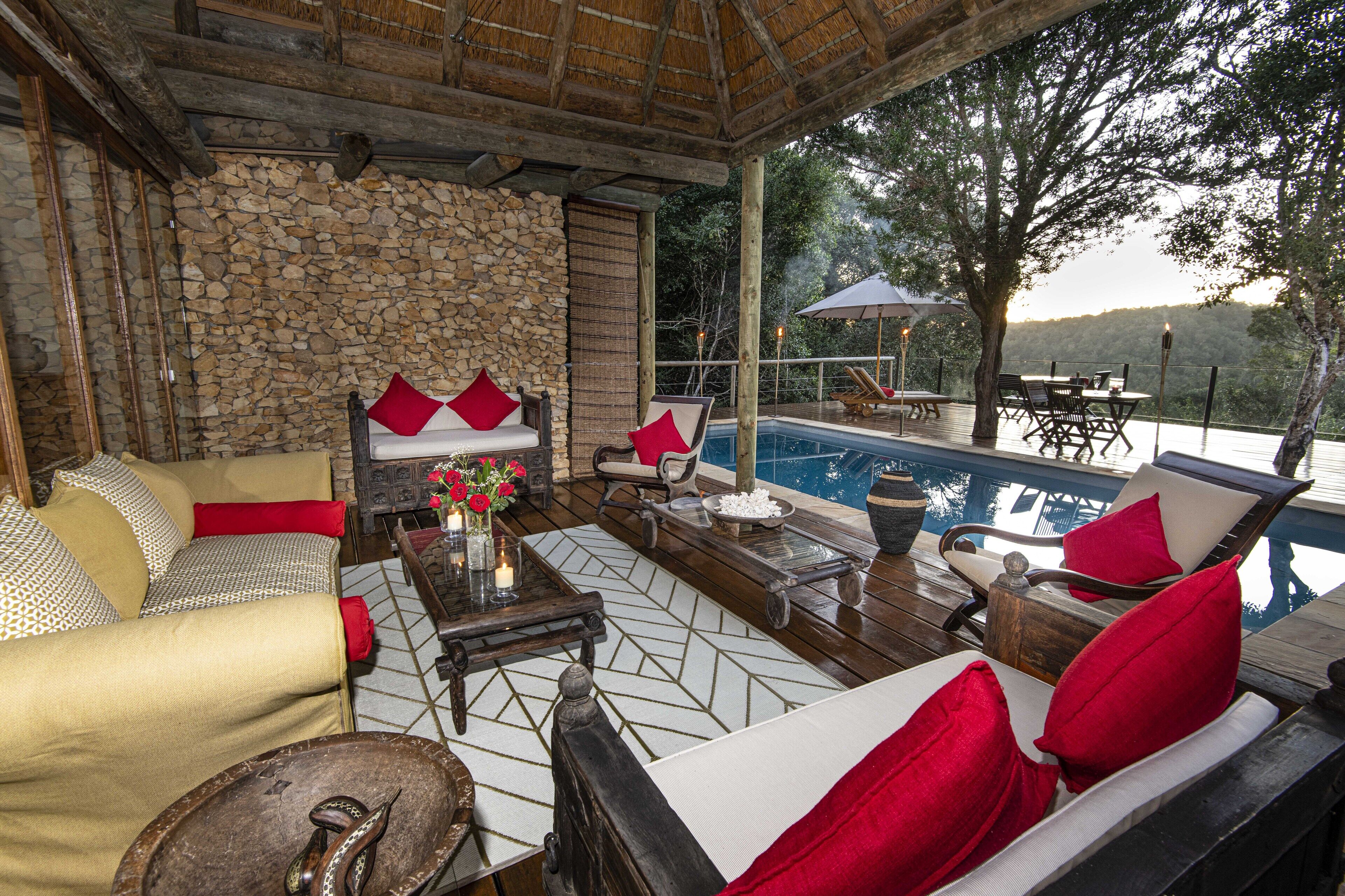 A cozy outdoor seating area with a stone wall, a pool, and a view of the surrounding landscape.