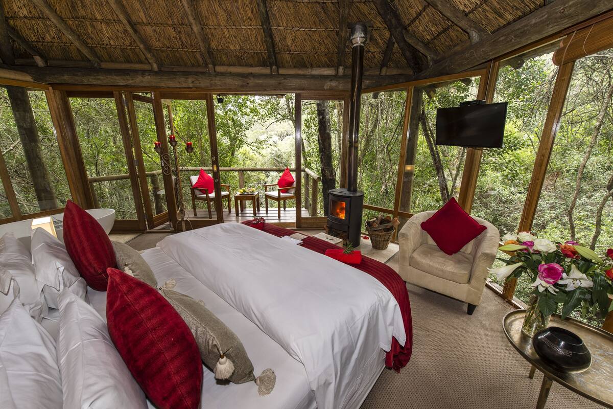 Una habitación acogedora con cama, sillón, chimenea y televisor.