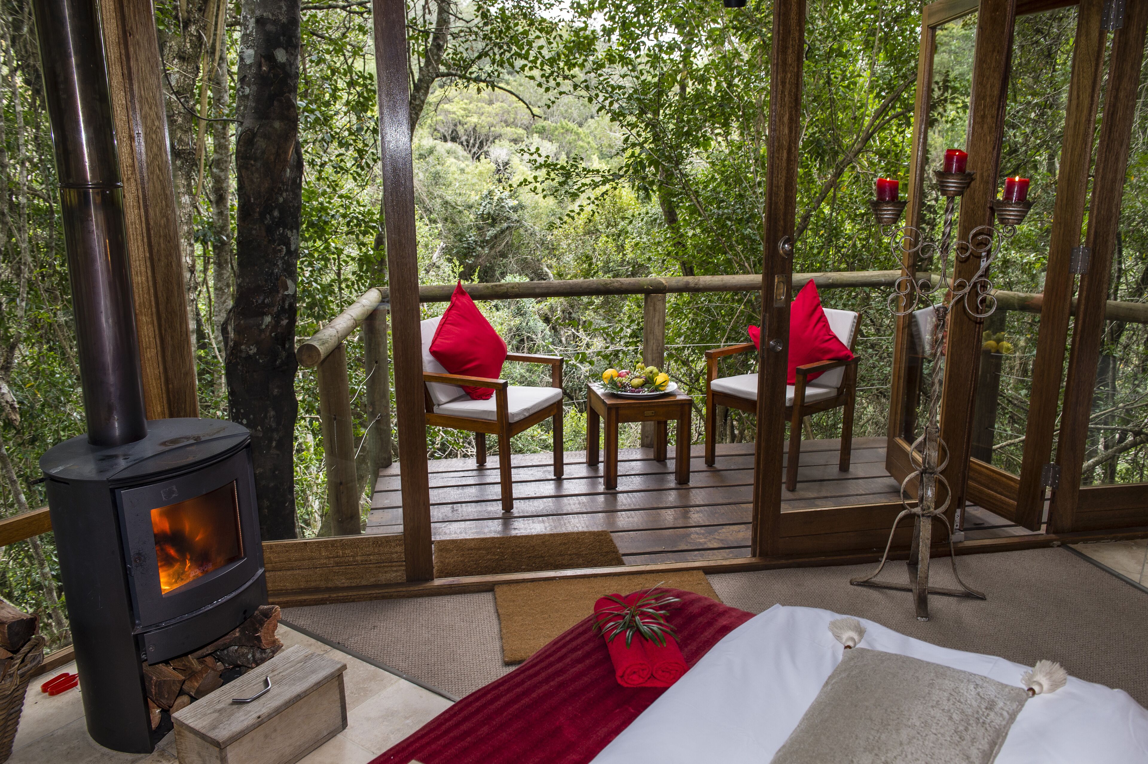 Una habitación acogedora con estufa de leña, cama y balcón con sillas y una mesa.