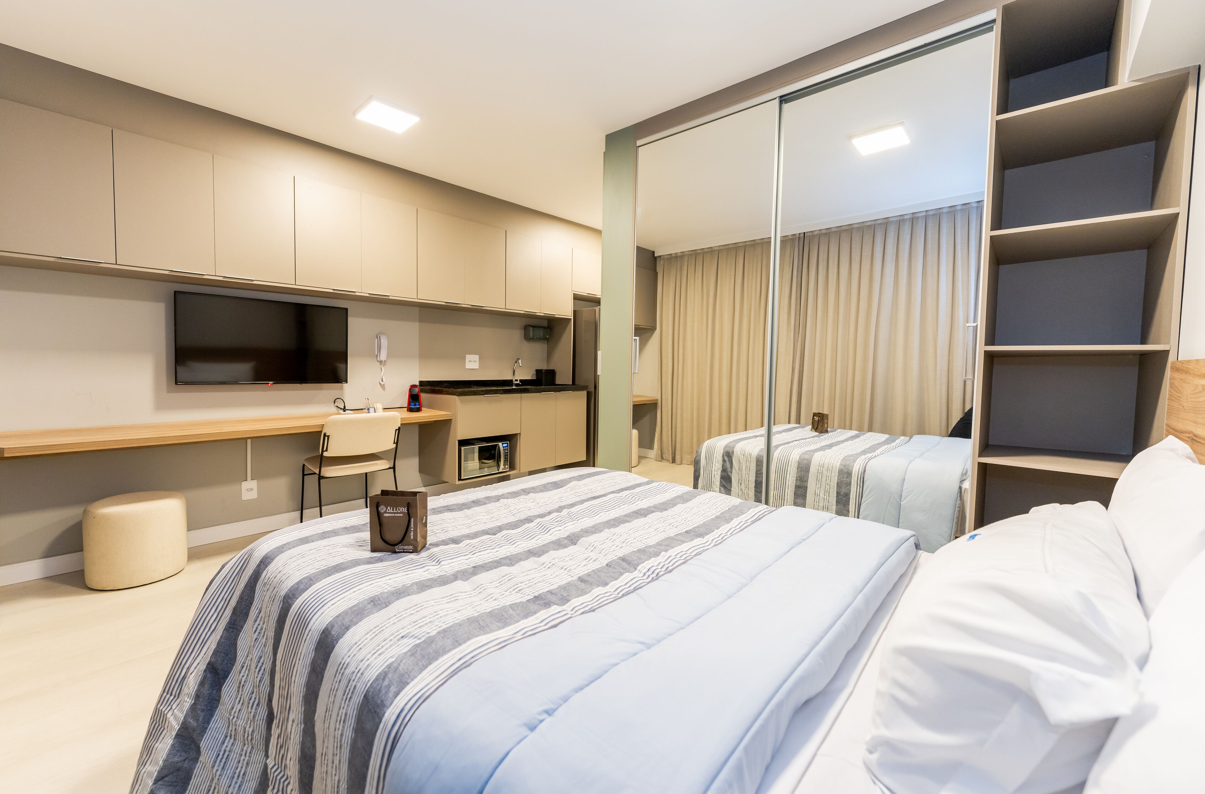 Ein modernes Hotelzimmer mit einem großen Bett, einem Schreibtisch, einem Flachbildfernseher und einem Kleiderschrank.