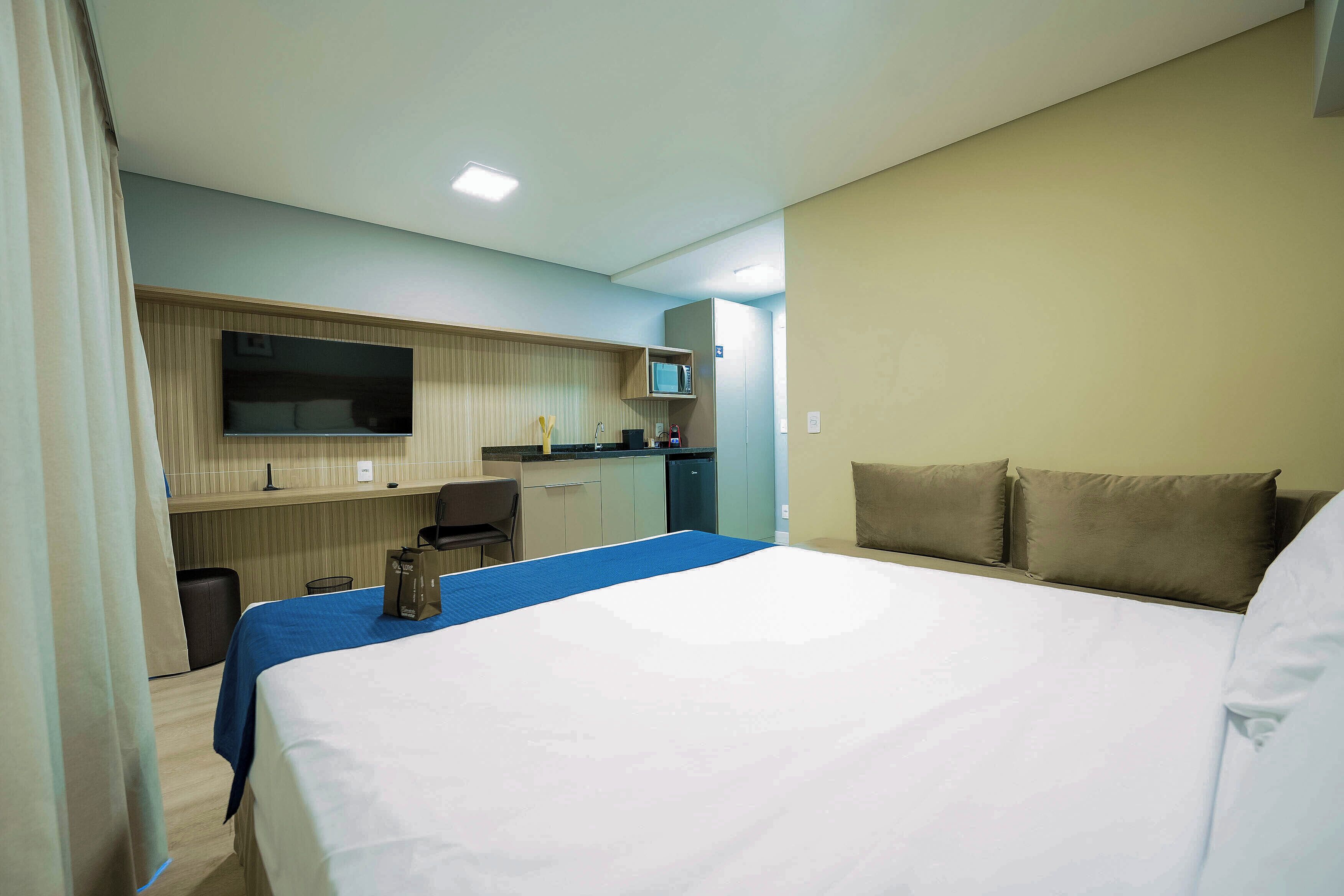 Ein Hotelzimmer mit Bett, Schreibtisch, Mikrowelle und Fernseher.
