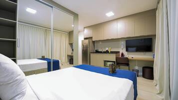 Une chambre d’hôtel équipée d’un lit, d’un bureau, d’une télévision et d’une kitchenette.