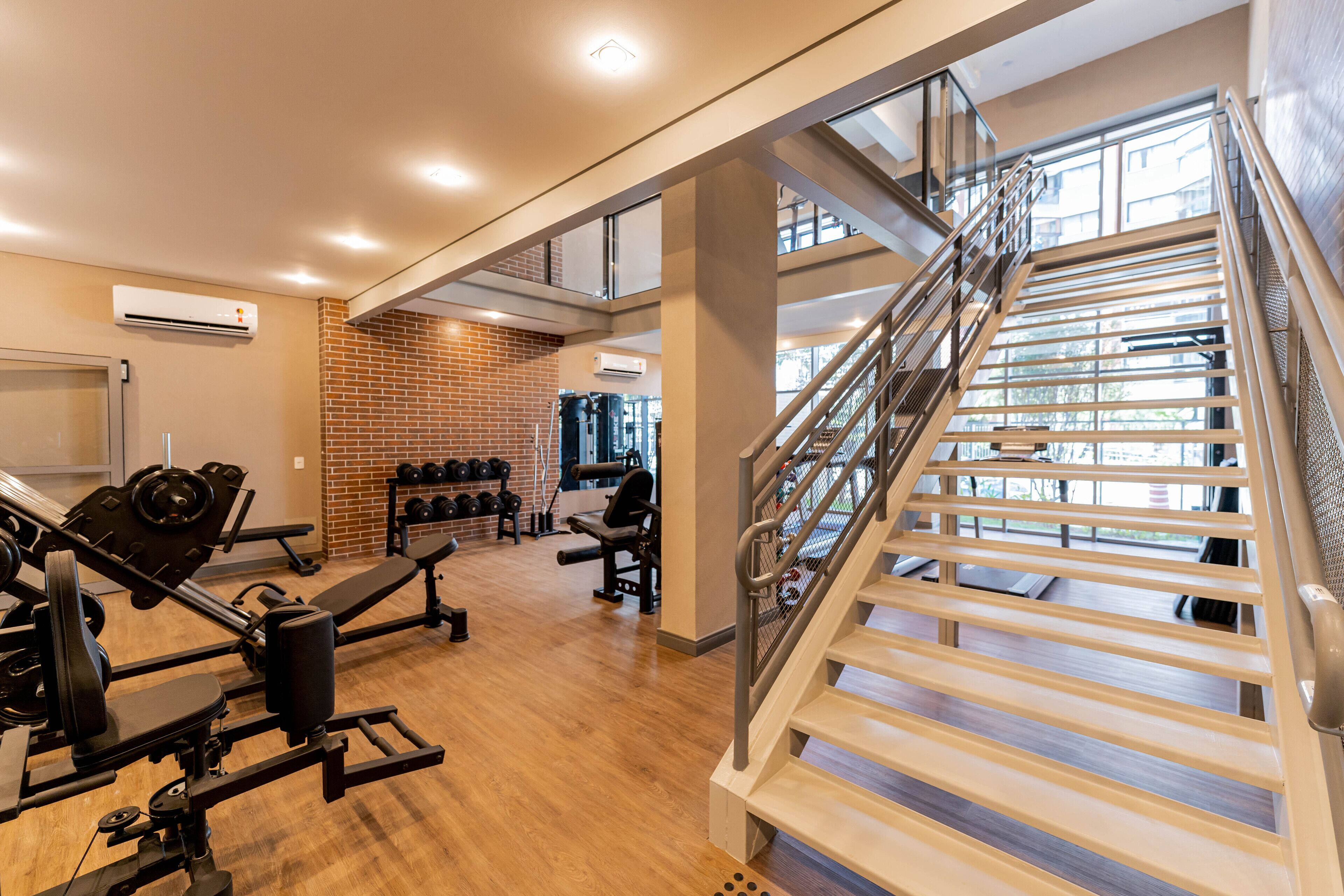 Un gimnasio con equipo de ejercicio, una pared de ladrillo y una escalera.