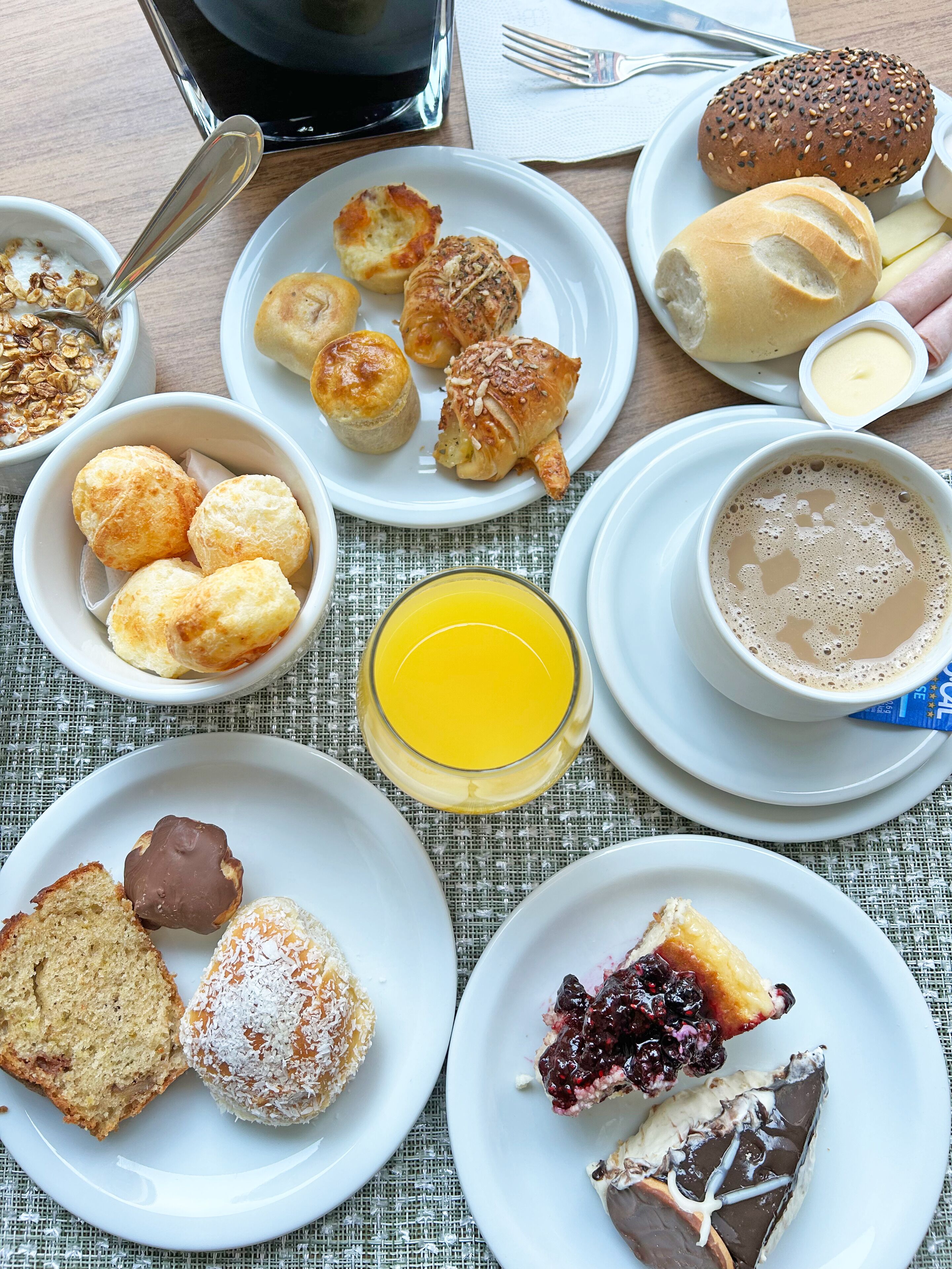 A breakfast setting with various pastries, a glass of orange juice, and a cup of coffee on a table.