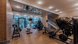A gym with weightlifting equipment, treadmills, and a staircase. - Apartamentos Studio Allure Moema (São Paulo)