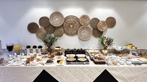 A buffet setup with various food items and a decorative wall with woven baskets. - Apartamentos Studio Allure Moema (São Paulo)