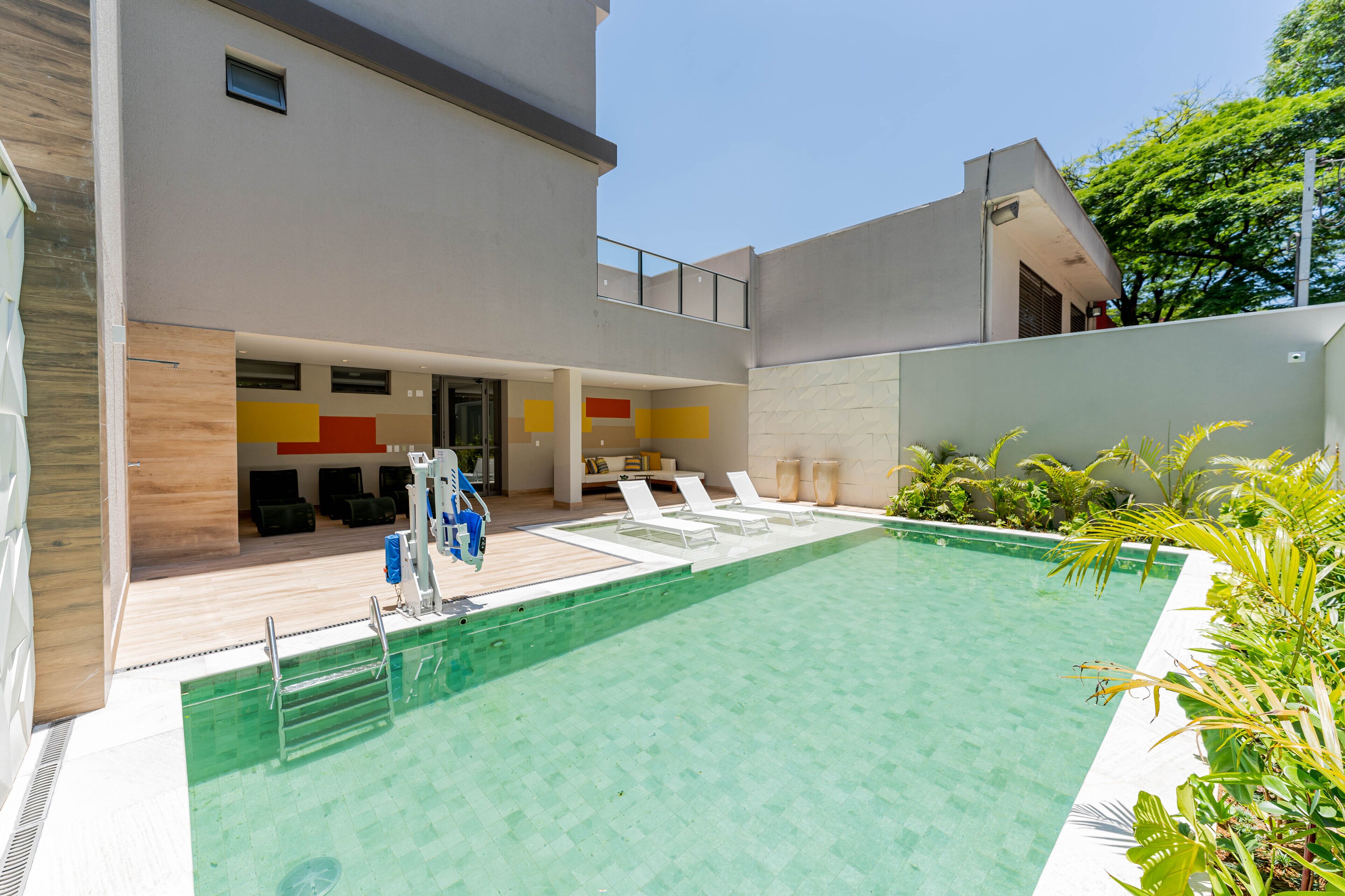 Ein modernes Hotel mit Schwimmbad, Liegestühlen und einer überdachten Sitzgelegenheit.