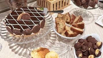 A table with various desserts including a cheesecake, chocolate-covered cookies, and pancakes.