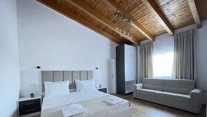 Ein modernes Schlafzimmer mit einem großen Bett, einer Couch, einem Kleiderschrank und einer Deckenleuchte.