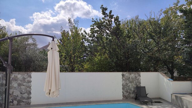A rectangular swimming pool with a stone wall and a metal structure on one side. - Villa Ivka with Swimming Pool (Dobrinj)