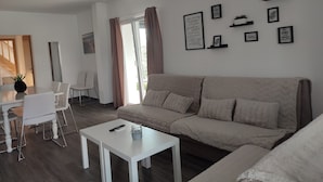 A modern living room with a beige sofa, white coffee table, and a dining area with a white table and chairs. - Villa Ivka with Swimming Pool (Dobrinj)