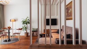 Un salon moderne avec un canapé, une table à manger et des chaises, une plante en pot et un tableau accroché au mur.