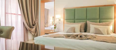 Une chambre d’hôtel avec un grand lit, une table de chevet, un miroir et une chaise.
