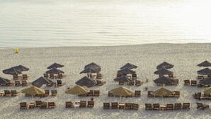 A beach with rows of wooden lounge chairs and thatched umbrellas, arranged in a neat pattern. - Hotel Marabout - Families and Couples Only (Sousse)