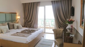 A hotel room with a bed, a chair, a table, a TV, and a balcony with curtains. - Hotel Marabout - Families and Couples Only (Sousse)