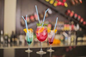 Tres cócteles con pajitas y adornos sobre una barra.