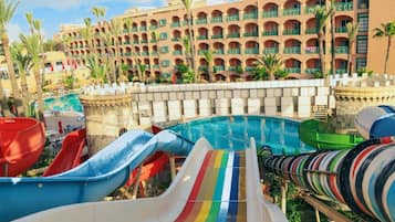 Une piscine d’hôtel avec plusieurs toboggans et, en arrière-plan, un grand bâtiment doté de balcons.