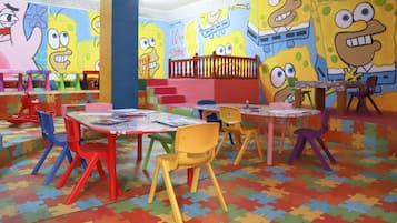 A children's playroom with colorful furniture and walls decorated with cartoon characters.