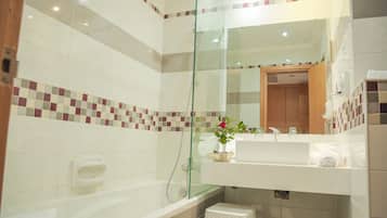 A modern bathroom with a glass-enclosed shower, a white sink, and a small stool.