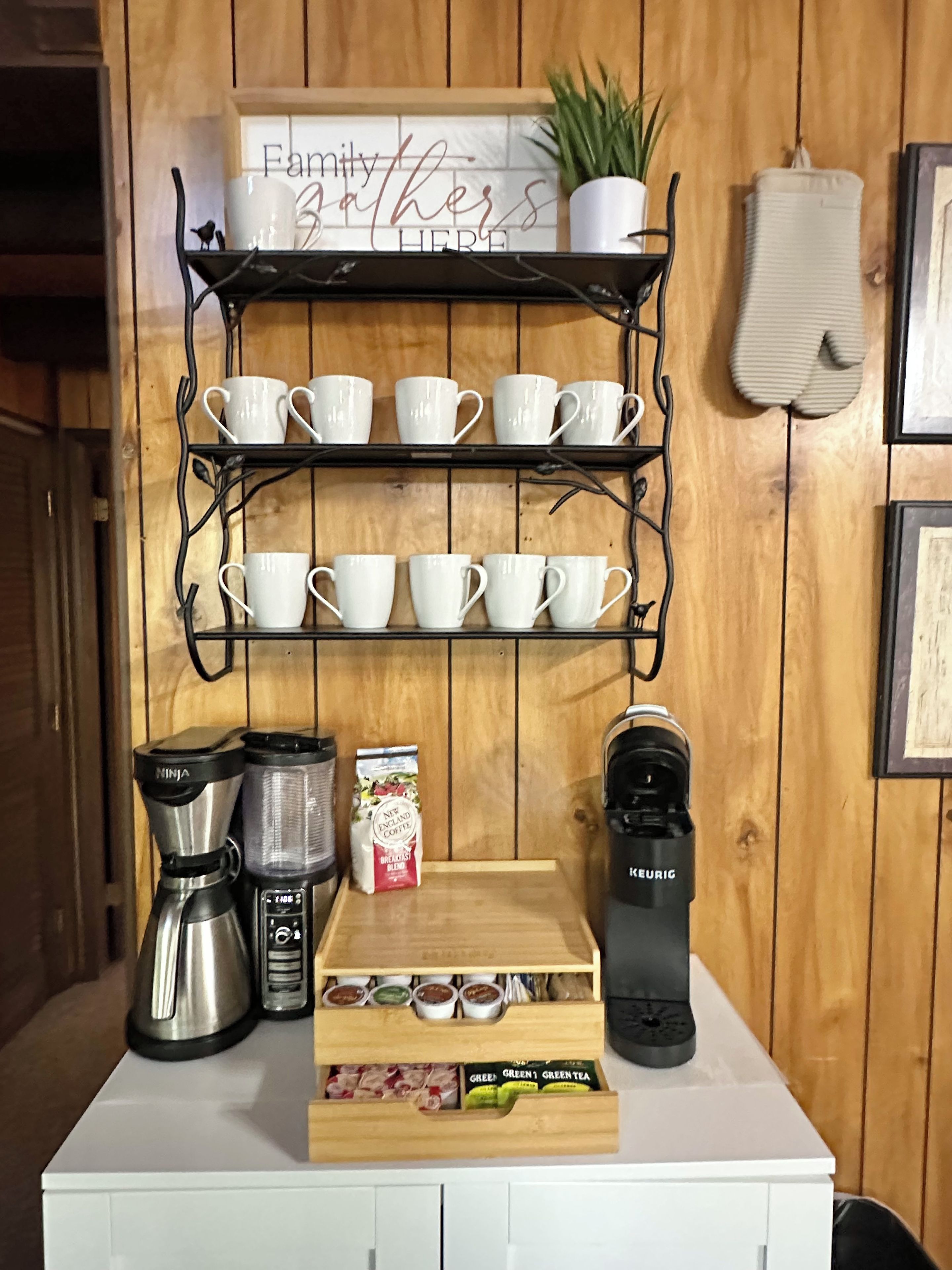 Eine Küchenarbeitsplatte mit einer Kaffeestation, darunter eine Kaffeemaschine, ein Keurig-System und eine Kaffeebohnenauslage.