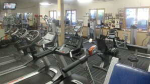 Une salle de sport équipée de plusieurs tapis de course, de vélos d’appartement et d’appareils de musculation.