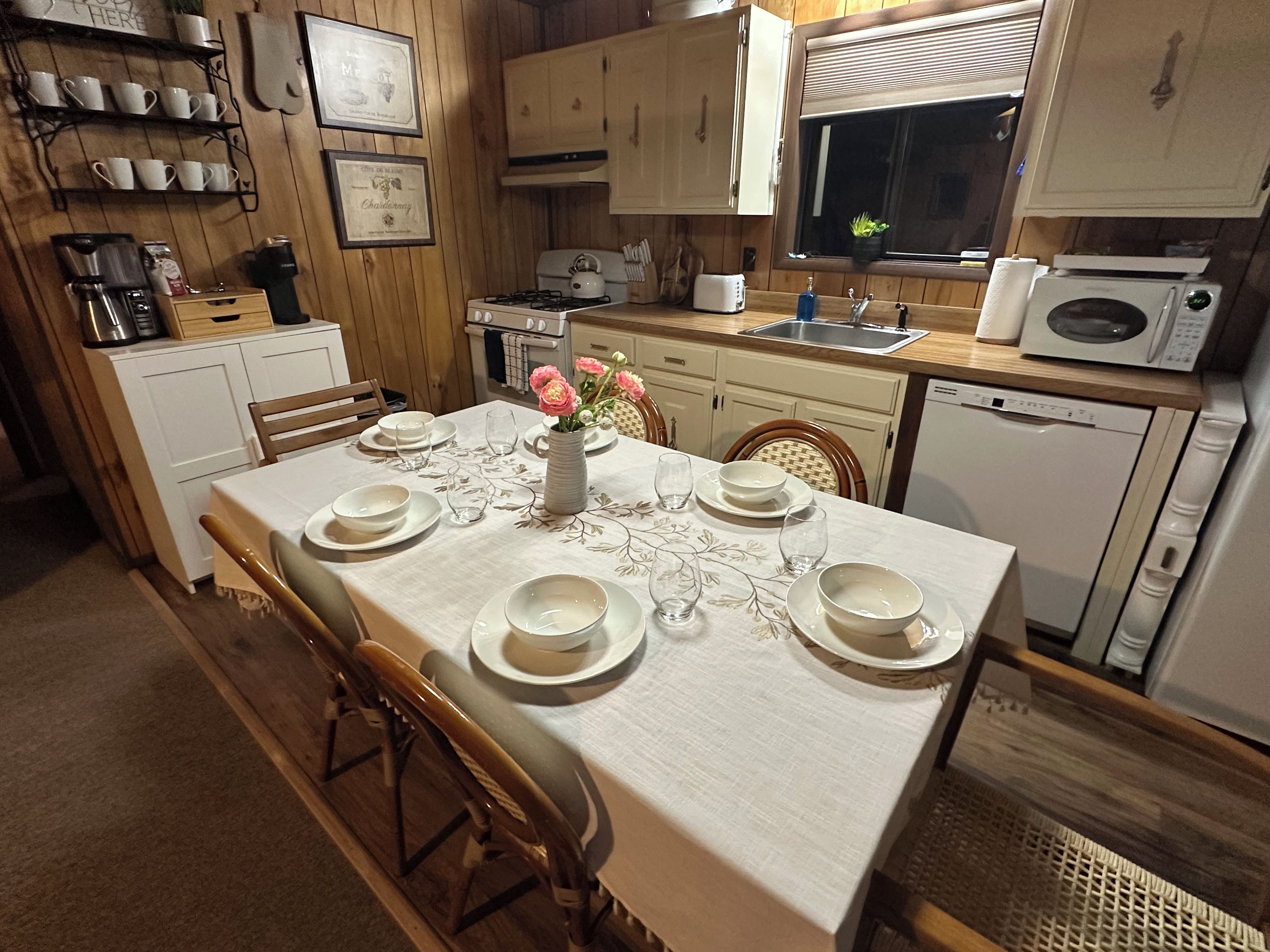Un coin repas avec une table dressée pour quatre personnes, une machine à café et un four à micro-ondes.