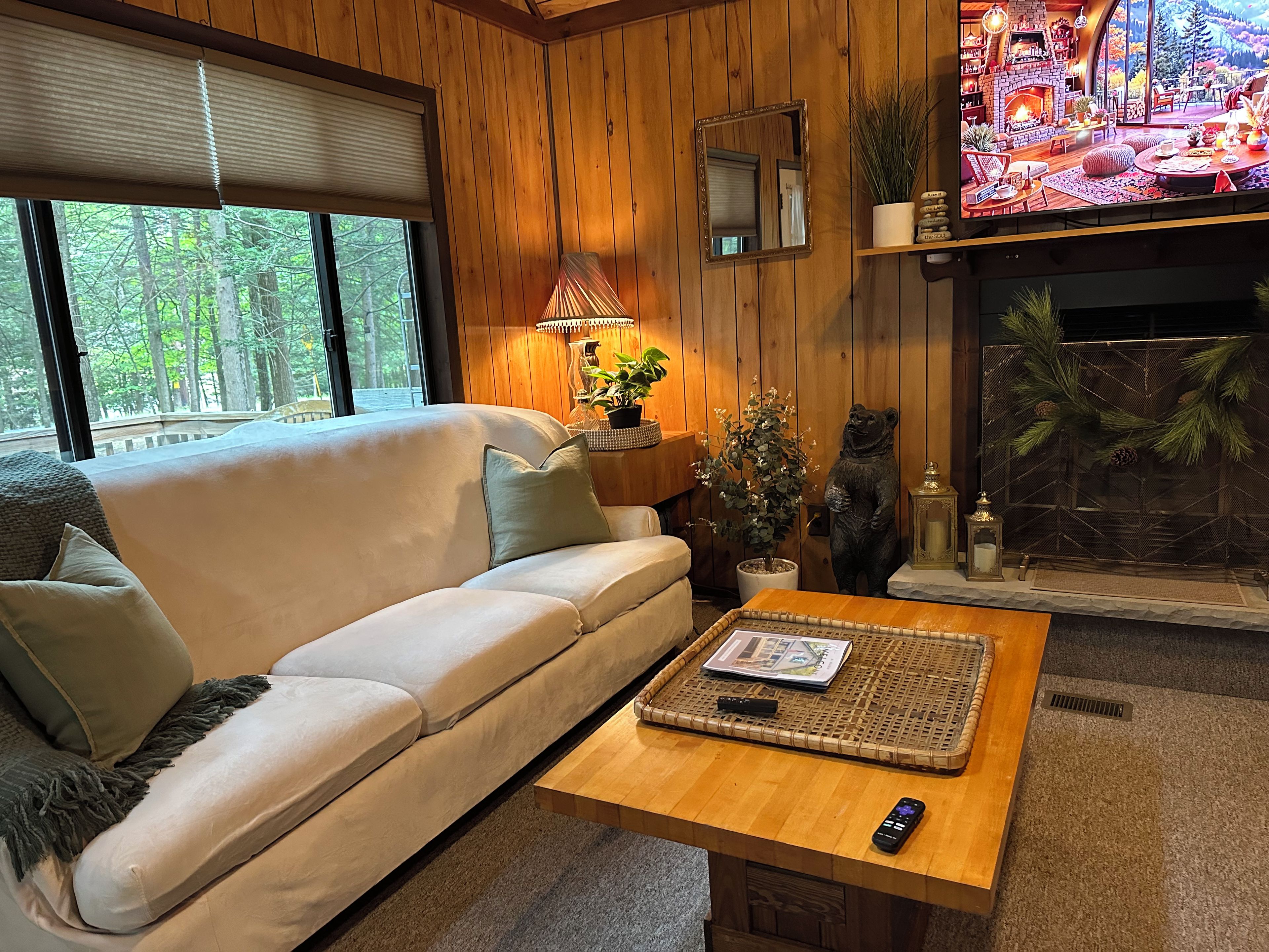 A cozy living room with a sofa, a coffee table, a fireplace, and a television.