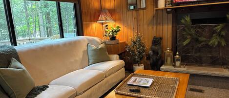 A cozy living room with a sofa, a coffee table, a fireplace, and a television.