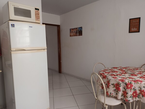 A kitchen with a refrigerator, a microwave, and a dining table with chairs.