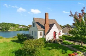 Situated on a well-maintained lawn, this charming home features a cozy porch and a prominent chimney.