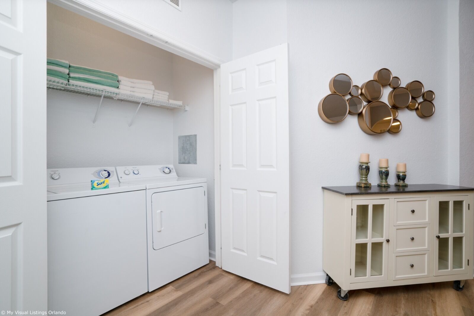 A laundry room with a washing machine, dryer, and neatly folded towels on a shelf.