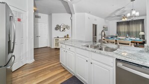 A modern kitchen with white cabinetry, granite countertops, and a built-in dishwasher. - VISTA CAY RESORT (Orlando)