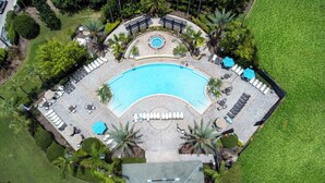 An aerial view of a resort with a large swimming pool, sun loungers, and palm trees. - VISTA CAY RESORT (Orlando)