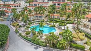 A resort with multiple buildings, a central swimming pool, and surrounding palm trees. - Beautiful luxury apartment with panoramic views of the Caribbean Sea (Willemstad)