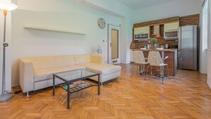 Un salon moderne comprenant un canapé, une table basse et un coin cuisine équipé d’un réfrigérateur, d’un four à micro-ondes et d’une table à manger avec des chaises.