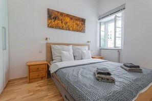 A bedroom with a bed, wooden nightstands, a window, and a painting on the wall. - Josef Manes birth house, WalkScore 99%, Old Town Square (Prague)