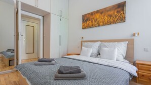 Une chambre à coucher avec un lit, une armoire, une table de chevet et un tableau au mur.