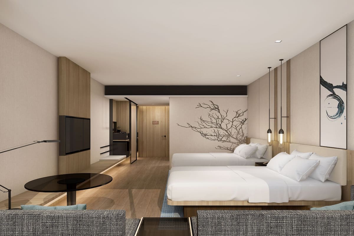 A modern hotel room with a large bed, a small table, a TV, and a wall-mounted artwork.