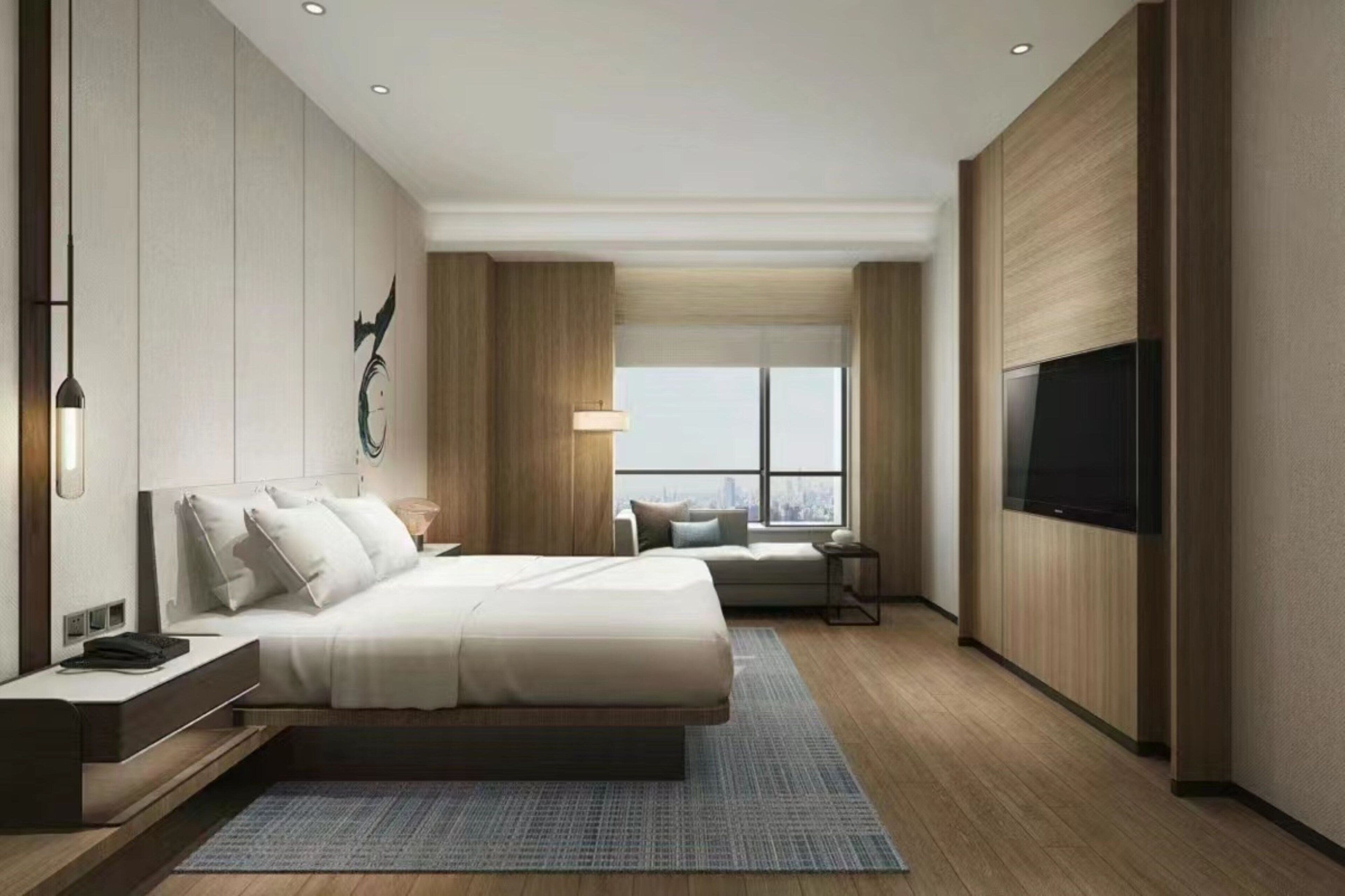 A modern hotel room with a large bed, a TV mounted on the wall, a city view, and a desk with a lamp.