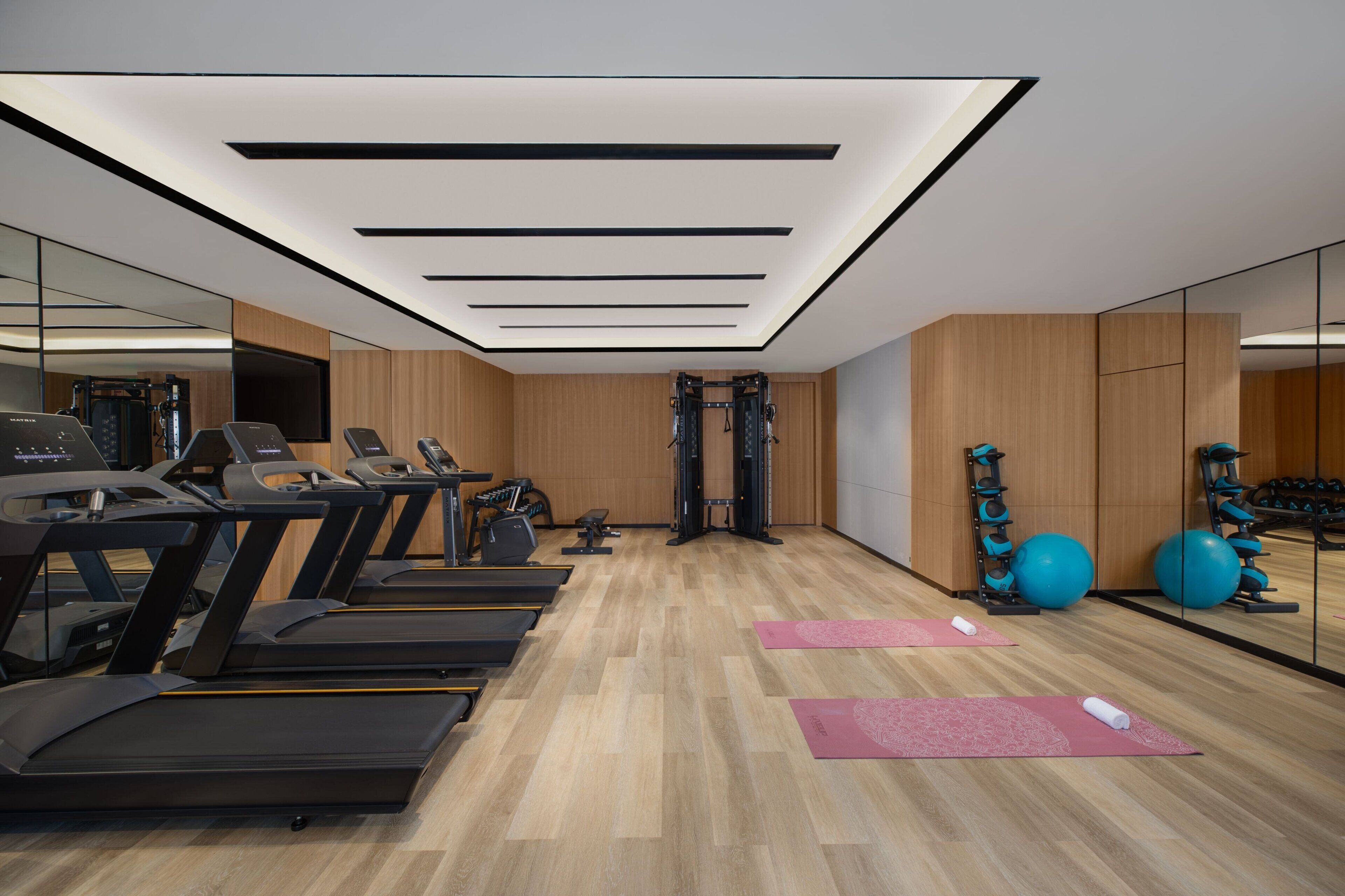 A gym with treadmills, exercise balls, and yoga mats.