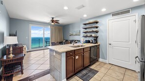 A modern kitchen with a large island, a built-in oven, and a view to the outside. - Sterling Breeze 1205 - Gulf Front Condo (Panama City Beach)