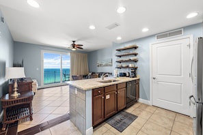 A modern kitchen with a large island, a built-in oven, and a view to the outside.