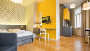 Een moderne hotelkamer met een bed, bureau, televisie en kitchenette.