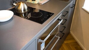 Een moderne keuken met een waterkoker, inductiekookplaat en roestvrijstalen apparatuur.