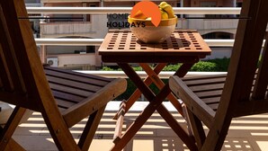 A balcony with wooden chairs and a table, overlooking a multi-story building with balconies. - #115 Bernardo Flat by Home Holidays (Albufeira)