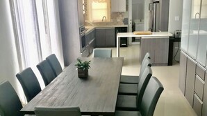 Et moderne spiseområde med et træbord, sorte stole og en potteplante.