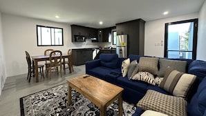 Ein modernes Wohnzimmer mit einem blauen Sofa, einem Holzespeisetisch und einer Küche im Hintergrund.